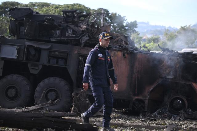 (FILES) A firefighters passes by a burnt military vehicle at La Carlota air base in Caracas on January 3, 2026, after US forces captured Venezuelan leader Nicolas Maduro after launching a "large scale strike" on the South American country. July 3, 2026 marks six months since the capture of Nicolas Maduro during a US military operation in Venezuela. (Photo by Federico PARRA / AFP)