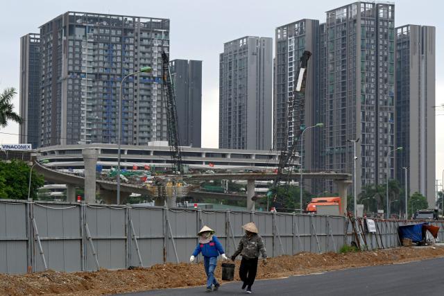 Workers walk together at an construction site in Hanoi on July 3, 2026. (Photo by Nhac NGUYEN / AFP)