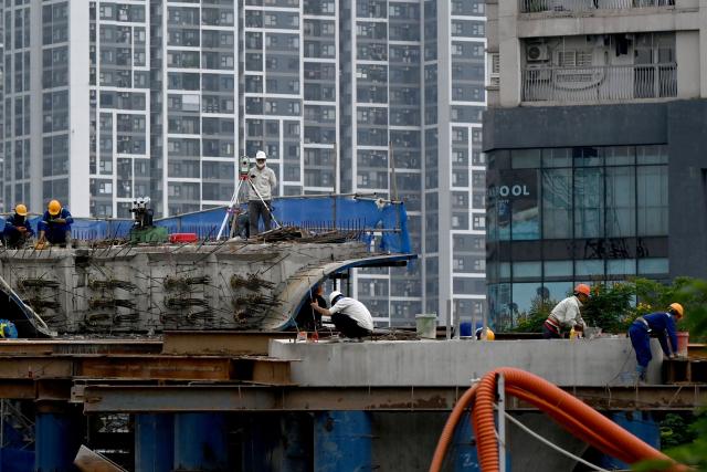 Workers are pictured at an overpass construction site in Hanoi on July 3, 2026. (Photo by Nhac NGUYEN / AFP)