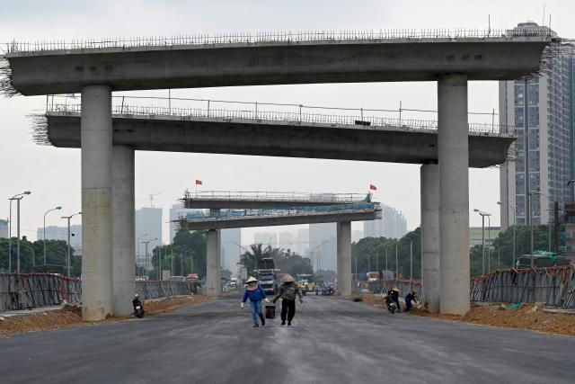 Workers walk together at an construction site in Hanoi on July 3, 2026. (Photo by Nhac NGUYEN / AFP)