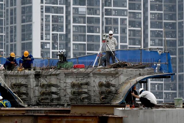 Workers are pictured at an overpass construction site in Hanoi on July 3, 2026. (Photo by Nhac NGUYEN / AFP)