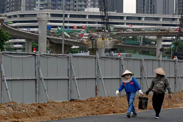 Workers walk together at a construction site in Hanoi on July 3, 2026. (Photo by Nhac NGUYEN / AFP)