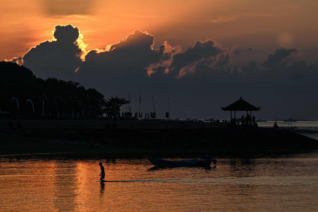 A man walks at a beach during sunrise in Sanur on Indonesia's resort island of Bali on July 3, 2026. (Photo by SONNY TUMBELAKA / AFP)