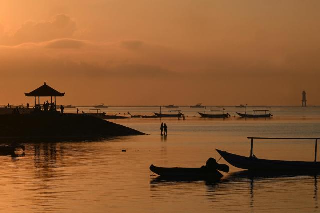 People enjoy the sunrise in Sanur on the Indonesia resort island of Bali on July 3, 2026. (Photo by SONNY TUMBELAKA / AFP)