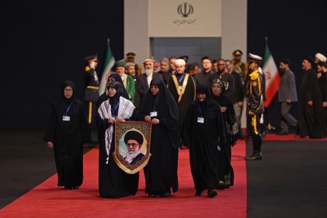 Local and foreign officials walk past the coffins of Iran's slain supreme leader Ali Khamenei and his family members after paying their respects at the Grand Mosalla in Tehran on July 3, 2026. The body of Iran's supreme leader Ali Khamenei, who was killed in US-Israeli strikes, arrived at Tehran's Grand Mosalla religious complex ahead of his funeral, state media reported on July 3. (Photo by Atta KENARE / AFP) / 
