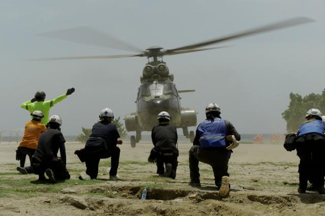 Rescue workers wait for a Venezuelan Air Force helicopter carrying supplies for earthquake survivors in La Guaira on July 2, 2026. More than a week after the earthquakes struck, there is little chance of finding additional survivors from the two earthquakes that killed nearly 2,500 people, destroyed entire residential buildings, and left tens of thousands missing. (Photo by Rosali Hernandez / AFP)
