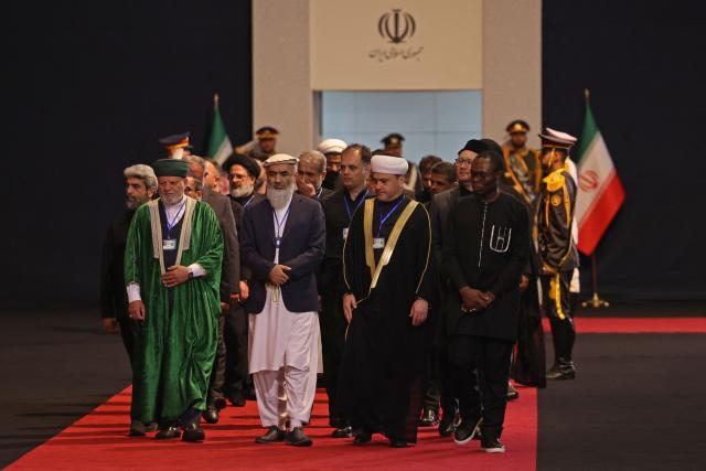 Members of Afghanistan's delegation walk past the coffins of Iran's slain supreme leader Ali Khamenei and his family members after paying their respects at the Grand Mosalla in Tehran on July 3, 2026. The body of Iran's supreme leader Ali Khamenei, who was killed in US-Israeli strikes, arrived at Tehran's Grand Mosalla religious complex ahead of his funeral, state media reported on July 3. (Photo by Atta KENARE / AFP) / 