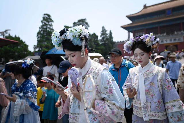 Tourists walk out of the Forbidden City on a hot day in Beijing on July 3, 2026. (Photo by WANG Zhao / AFP)