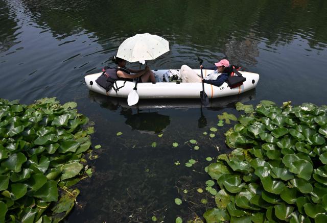 People row an inflatable boat on the Liangma River during summer in Beijing on July 3, 2026. (Photo by ADEK BERRY / AFP)