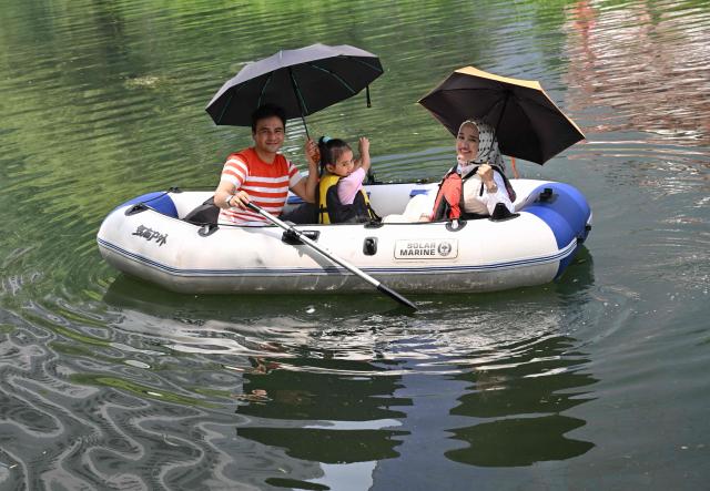 People row an inflatable boat on the Liangma River during summer in Beijing on July 3, 2026. (Photo by ADEK BERRY / AFP)