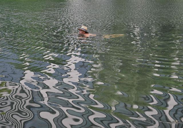A man swims in the Liangma River during summer in Beijing on July 3, 2026. (Photo by ADEK BERRY / AFP)