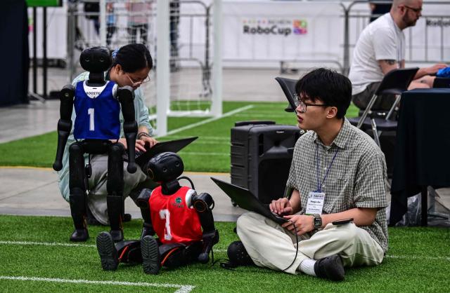 Participants prepare their robots for a football match at RoboCup 2026, a robotics and Artificial Intelligence (AI) competition in Incheon on July 3, 2026. (Photo by Jade GAO / AFP)