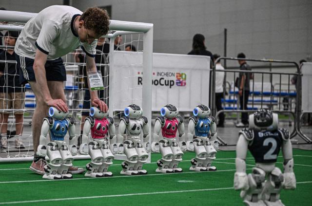 A participant prepares his robots ahead of a football match at RoboCup 2026, a robotics and Artificial Intelligence (AI) competition in Incheon on July 3, 2026. (Photo by Jade GAO / AFP)