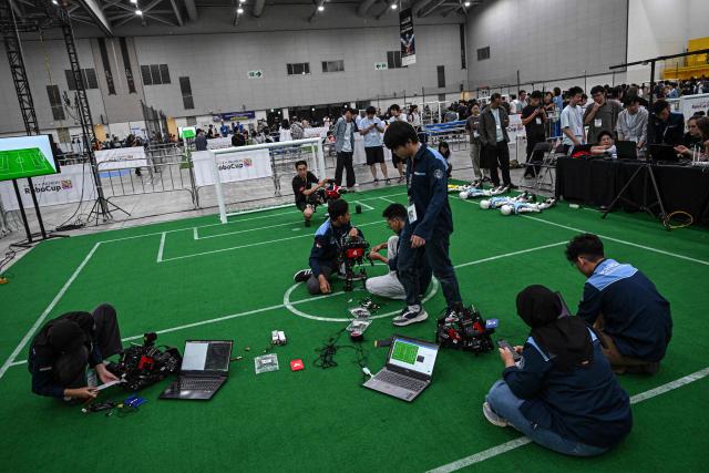 Participants prepare their robots for a football match at RoboCup 2026, a robotics and Artificial Intelligence (AI) competition in Incheon on July 3, 2026. (Photo by Jade GAO / AFP)