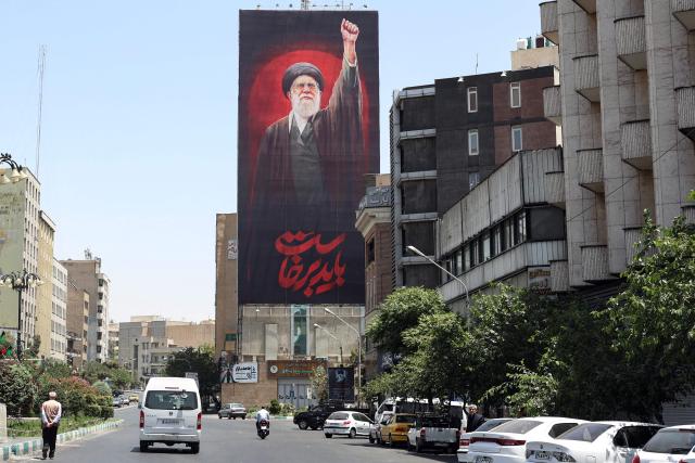 Motorists drive past a billboard bearing a picture of Iran's slain supreme leader Ali Khamenei, ahead of his funeral in Tehran on July 3, 2026. Iranian leaders began paying their respects on July 3 before the coffin of the country's late supreme leader Ali Khamenei, killed in the US-Israeli strikes that triggered the Middle East war, as Tehran prepared for a vast funeral. Khamenei's body arrived at Tehran's Grand Mosalla on July 3 ahead of ceremonies which are expected to draw millions. (Photo by AFP) / 