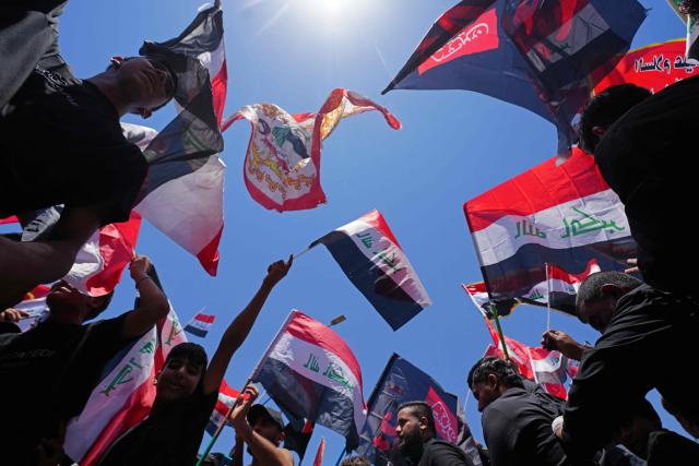 Supporters of Shia cleric Muqtada al-Sadr, wave flags as they take part in a demonstration supporting Iraqi Prime Minister Ali al-Zaidi’s government-led anti-corruption campaign, in Najaf on July 3, 2026. Iraq's new prime minister, Ali al-Zaidi, who recently took office with the blessing of the United States, has made two main vows: to fight corruption and to ensure a state monopoly on weapons. (Photo by Qassem al-KAABI / AFP)