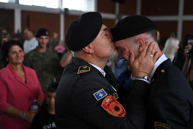 Former Kosovo Liberation Army Soldier Safet Saly (L) embraces his son, a Kosovo Security Force (KSF) cadet, during a graduation ceremony at Adem Jashari barracks in Pristina on July 3, 2026. (Photo by Armend NIMANI / AFP)