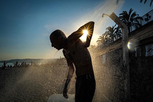 (FILES) A man takes a shower on the beach along the "Promenade des anglais" on the French riviera city of Nice, on June 26, 2026. With a heatwave of unprecedented intensity and a string of temperature records shattered across the country, June 2026 has become the hottest June ever recorded in France, national weather service Meteo-France announced on July 3, 2026. (Photo by Valery HACHE / AFP)
