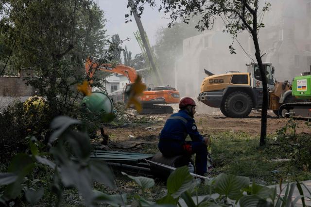 A rescue worker sits on a bench near a residential building damaged following a Russian air attack on the Ukrainian capital of Kyiv on July 3, 2026, amid the Russian invasion in Ukraine. Russia launched its largest ever barrage on Kyiv early July 2, 2026, according to the city's mayor, tearing open apartment buildings in an hours-long drone and missile attack that killed at least 30 people. (Photo by Tetiana DZHAFAROVA / AFP)