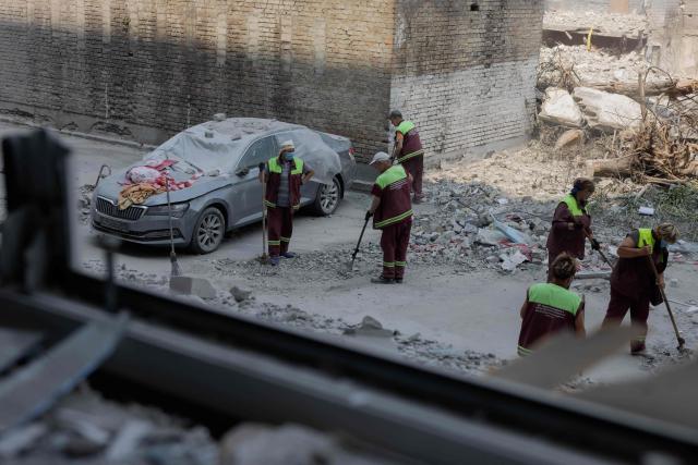Workers are sweeping debris off the street near a residential building damaged following a Russian air attack on the Ukrainian capital of Kyiv on July 3, 2026, amid the Russian invasion in Ukraine. Russia launched its largest ever barrage on Kyiv early July 2, 2026, according to the city's mayor, tearing open apartment buildings in an hours-long drone and missile attack that killed at least 30 people. (Photo by Tetiana DZHAFAROVA / AFP)