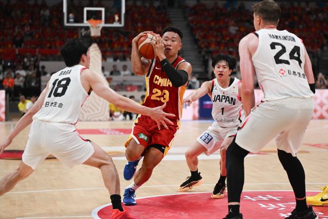 China’s He Xining controls the ball as Japan’s Takumi Saito, Yudai Baba and Joshua Hawkinson block during the FIBA Basketball World Cup 2027 Asian Qualifiers game between China and Japan in Shenyang, China’s Liaoning Province on July 3, 2026. (Photo by CN-STR / AFP) / China OUT