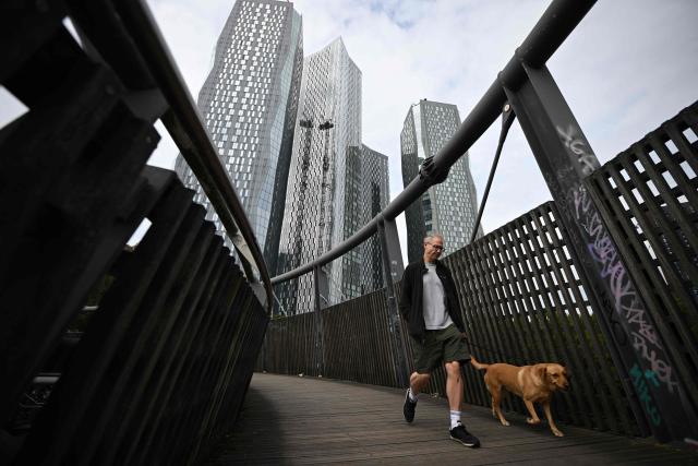 A dog is walked below tower blocks in the Deansgate area of Manchester, north west England on July 3, 2026. (Photo by Oli SCARFF / AFP)