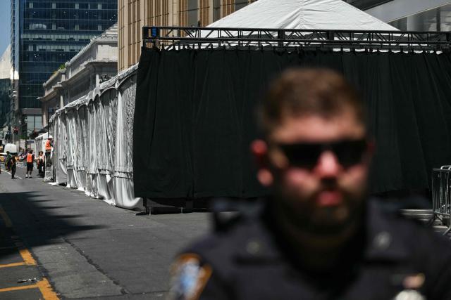 A New York City Police officer stands watch as workers make adjustments to a tent outside Madison Square Garden, the reported venue for the wedding celebrations of pop singer Taylor Swift and pro-athlete Travis Kelce, in New York City on July 3, 2026. Swift and Kelce's official wedding plans are tightly under wraps, but New York is bracing to host the celebrity marriage of the year this week at Madison Square Garden. The wedding will reportedly take place Friday with a star-studded guest list of around 1,000, including models Gigi Hadid and Cara Delevingne, singer Selena Gomez, and actress Zoe Kravitz -- all known to be close Swift pals -- and Kelce's Kansas City Chiefs teammates. (Photo by ANGELA WEISS / AFP)