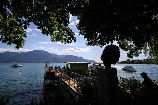 This photograph shows a bust statue of the late US trumpeter, bandleader and composer Miles Davis silhouetted on the shore of Lake Geneva on the opening day of the 60th Montreux Jazz Festival in Montreux, Switzerland, on July 3, 2026. (Photo by Fabrice COFFRINI / AFP)