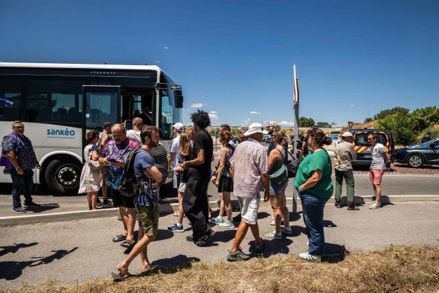 Residents of the camping 'Le Brasilia' wait for a bus to reach their camping a day after a wildfire broke out, on the road to the port of Canet-en-Roussillon, southern France on July 3, 2026. Nearly 3,000 people had to be evacuated from several campsites, as well as from businesses and several municipalities, after a fire broke out in Sainte-Marie-la-Mer and spread on to Canet-en-Roussillon, affecting the watersports hub, firefighters and the prefect of Pyrenees-Orientales said on July 2, 2026. (Photo by Jc Milhet / AFP)