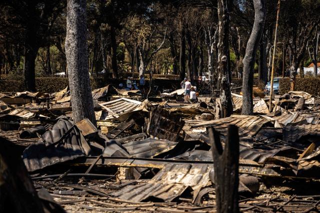 Poeple look at debris in the camping 'Le Brasilia', a day after a fire broke out, in Canet-en-Roussillon, southern France on July 3, 2026. Nearly 3,000 people had to be evacuated from several campsites, as well as from businesses and several municipalities, after a fire broke out in Sainte-Marie-la-Mer and spread on to Canet-en-Roussillon, affecting the watersports hub, firefighters and the prefect of Pyrenees-Orientales said on July 2, 2026. (Photo by Jean-Christophe MILHET / AFP)