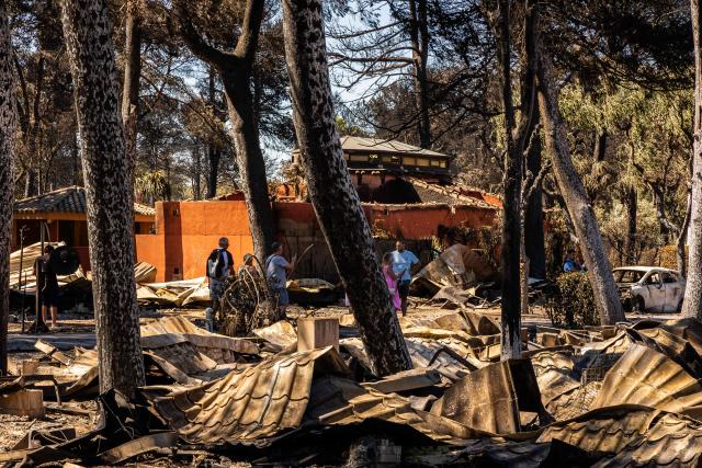 People look at debris in the camping 'Le Brasilia', a day after a fire broke out, in Canet-en-Roussillon, southern France on July 3, 2026. Nearly 3,000 people had to be evacuated from several campsites, as well as from businesses and several municipalities, after a fire broke out in Sainte-Marie-la-Mer and spread on to Canet-en-Roussillon, affecting the watersports hub, firefighters and the prefect of Pyrenees-Orientales said on July 2, 2026. (Photo by Jean-Christophe MILHET / AFP)