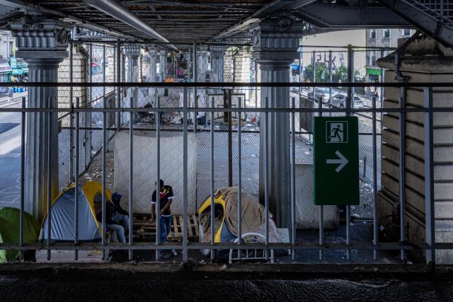 Homeless men speak with each other at a makeshift camp set up beneath the elevated Stalingrad metro station in Paris on July 3, 2026. (Photo by JOEL SAGET / AFP)