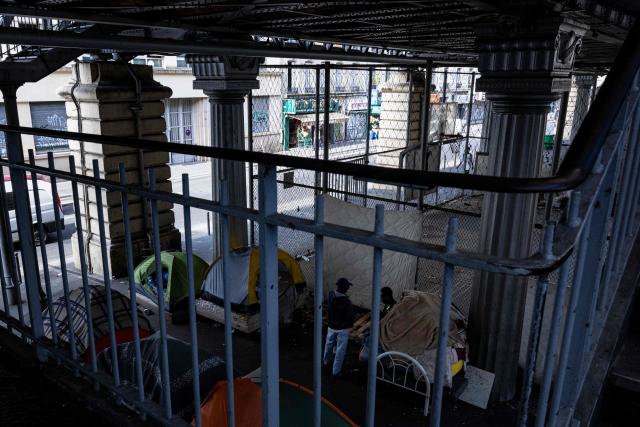 Homeless men speak with each other at a makeshift camp set up beneath the elevated Stalingrad metro station in Paris on July 3, 2026. (Photo by JOEL SAGET / AFP)