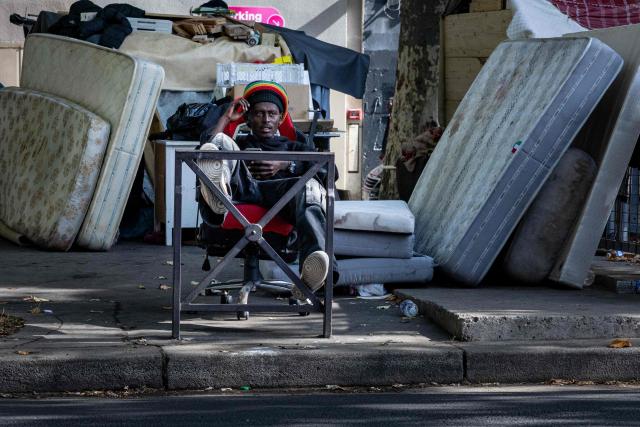 A homeless man looks on from a chair at a makeshift camp set up beneath the elevated Stalingrad metro station in Paris on July 3, 2026. (Photo by JOEL SAGET / AFP)