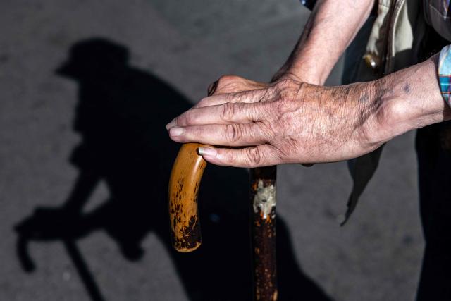 This photograph shows the hands of an elderly man as he leans on his cane, in Paris on July 3, 2026. (Photo by JOEL SAGET / AFP)