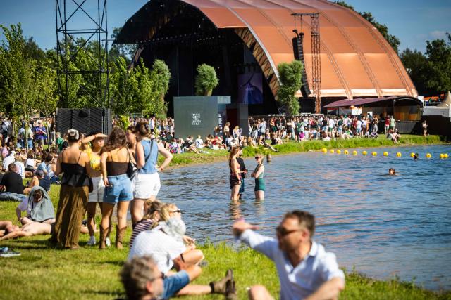 Festival-goers relax on the shore of the Groene Heuvels lake during the first day of the Down the Rabbit Hole music festival in Beuningen, eastern Netherlands on July 3, 2026. (Photo by Marcel Krijgsman / ANP / AFP) / Netherlands OUT