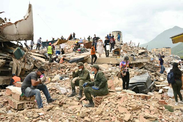 Rescuers rest amid the rubble of collapsed buildings in Caraballeda, La Guaira state, Venezuela, on July 3, 2026. The death toll from Venezuela's twin earthquakes has risen to 2,595, Interim President Delcy Rodriguez said on July 2. (Photo by MARTIN BERNETTI / AFP)