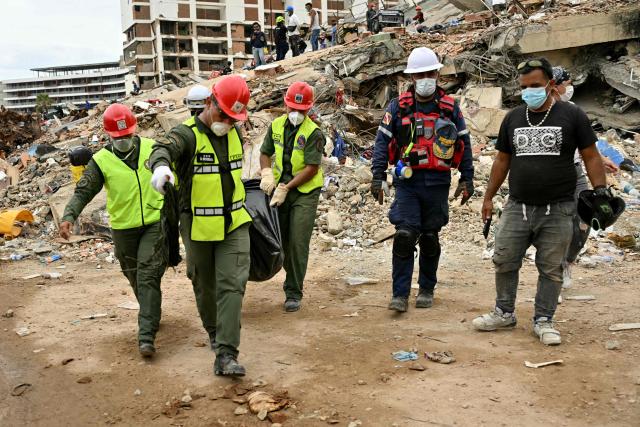 Rescuers carry a body in a bag recovered from the rubble of a collapsed building in Caraballeda, La Guaira state, Venezuela, on July 3, 2026. The death toll from Venezuela's twin earthquakes has risen to 2,595, Interim President Delcy Rodriguez said on July 2. (Photo by MARTIN BERNETTI / AFP)