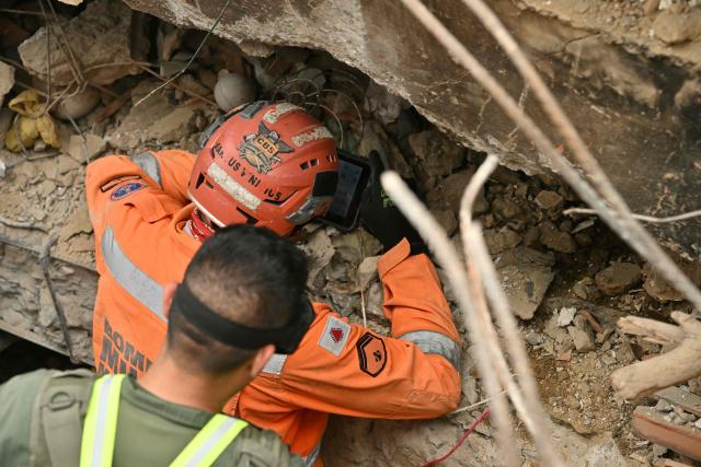 A rescuer uses a handheld device to search beneath the rubble of a collapsed building in Caraballeda, La Guaira state, Venezuela, on July 3, 2026. The death toll from Venezuela's twin earthquakes has risen to 2,595, Interim President Delcy Rodriguez said on July 2. (Photo by MARTIN BERNETTI / AFP)