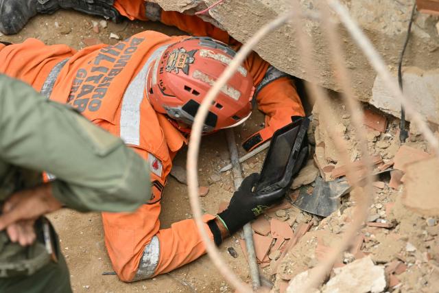 A rescuer uses a handheld device to search beneath the rubble of a collapsed building in Caraballeda, La Guaira state, Venezuela, on July 3, 2026. The death toll from Venezuela's twin earthquakes has risen to 2,595, Interim President Delcy Rodriguez said on July 2. (Photo by MARTIN BERNETTI / AFP)