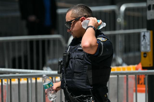 A New York City Police (NYPD) officer cools down with a bottle of water in Midtown Manhattan during a heatwave in New York City on July 3, 2026. Blistering temperatures and humidity has gripped swaths of the United States this week, with more to come for the densely populated East Coast as the nation co-hosts the World Cup and prepares to celebrate its 250th birthday on July 4. The heat wave that has been broiling the Midwest is intensifying in the Northeast, with temperatures surpassing 100F (38C) in cities including New York, Philadelphia and Washington. (Photo by ANGELA WEISS / AFP)