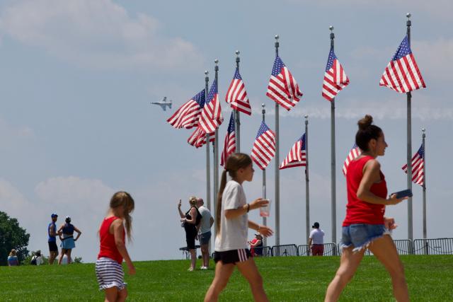 People gather on the National Mall as a US Air Force Thunderbirds demonstration squadron flies overhead in Washington, DC, on July 3, 2026, ahead of the upcoming July 4 holiday. (Photo by Amid FARAHI / AFP)