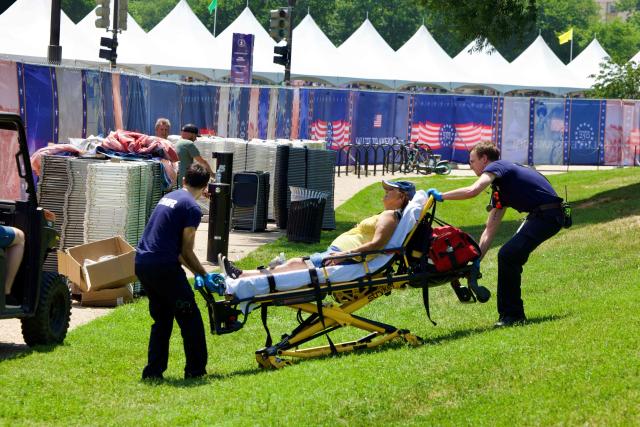 A person is helped by first responders as people cope with extreme heat along the National Mall in Washington, DC, on July 3, 2026, as high temperatures grip the US capital ahead of Independence Day celebrations. Blistering temperatures and humidity has gripped swaths of the United States this week, with more to come for the densely populated East Coast as the nation co-hosts the World Cup and prepares to celebrate its 250th birthday on July 4. The heat wave that has been broiling the Midwest is intensifying in the Northeast, with temperatures surpassing 100F (38C) in cities including New York, Philadelphia and Washington. (Photo by Amid FARAHI / AFP)