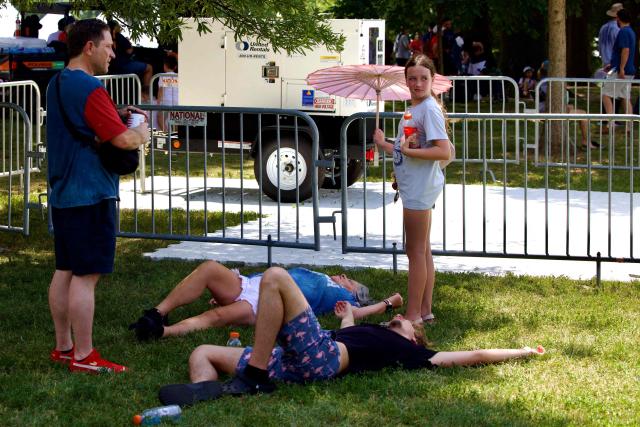 People lie on the grass in the shade of a tree as people cope with extreme heat along the National Mall in Washington, DC, on July 3, 2026, as high temperatures grip the US capital ahead of Independence Day celebrations. Blistering temperatures and humidity has gripped swaths of the United States this week, with more to come for the densely populated East Coast as the nation co-hosts the World Cup and prepares to celebrate its 250th birthday on July 4. The heat wave that has been broiling the Midwest is intensifying in the Northeast, with temperatures surpassing 100F (38C) in cities including New York, Philadelphia and Washington. (Photo by Amid FARAHI / AFP)