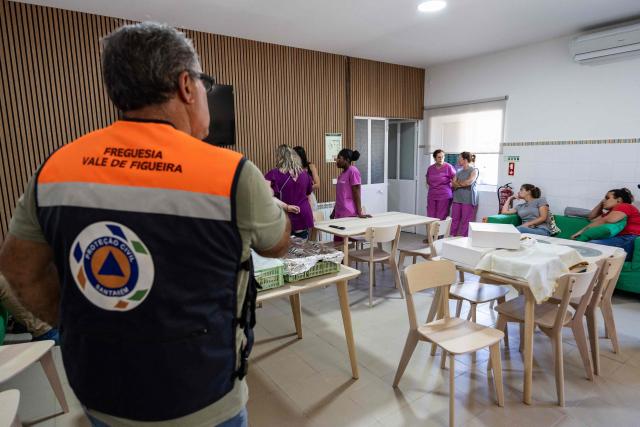 Rui Apolinario (L), president of the parish of Vale de Figueira, meets with staff at the Vale de Figueira Social Welfare Center in Santarem, Portugal, on July 3, 2026, where elderly residents spend the day. Parts of Portugal are under red alert due to forecast high temperatures in the coming days after being relatively spared by the recent European heatwave, with the IPMA weather agency placing regions including Leiria and Coimbra on alert through Friday as temperatures could reach 44°C in some areas. (Photo by HENRIQUE CASINHAS / AFP)