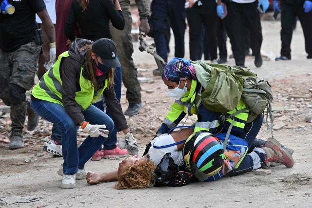 Volunteers comfort a person after the body of a relative was recovered from the rubble of a collapsed building in Caraballeda, La Guaira state, Venezuela, on July 3, 2026. The death toll from Venezuela's devastating twin earthquakes has risen to 2,645, with more than 12,600 injured, according to new official figures released on July 3. (Photo by MARTIN BERNETTI / AFP)