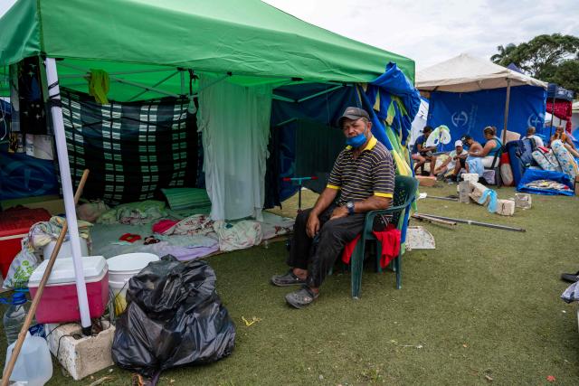 Displaced people take shelter in tents at the Cesar Nieves baseball stadium in the La Angustia neighborhood of Catia La Mar, La Guaira state, Venezuela, on July 3, 2026. The death toll from Venezuela's devastating twin earthquakes has risen to 2,645, with more than 12,600 injured, according to new official figures released on July 3. (Photo by Miguel MEDINA / AFP)