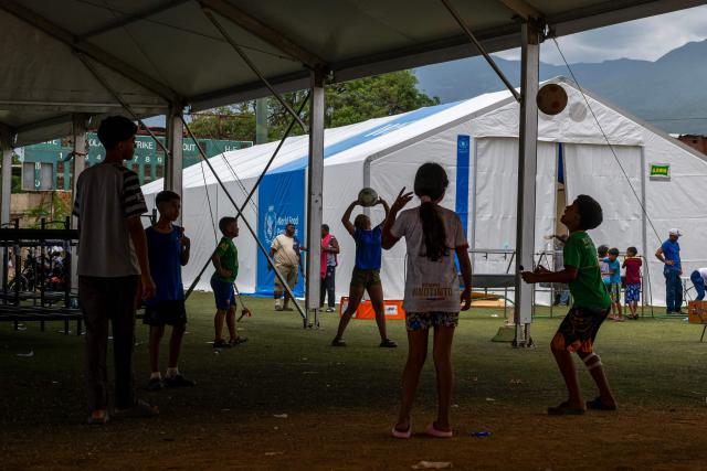 Children play with a ball inside a tent shelter at the Cesar Nieves baseball stadium in the La Angustia neighborhood of Catia La Mar, La Guaira state, Venezuela, on July 3, 2026, where displaced people have taken refuge. The death toll from Venezuela's devastating twin earthquakes has risen to 2,645, with more than 12,600 injured, according to new official figures released on July 3. (Photo by Miguel MEDINA / AFP)