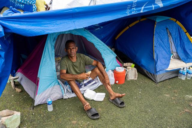 A displaced man sits at the entrance of a tent at the Cesar Nieves stadium in the La Angustia neighborhood of Catia La Mar, La Guaira state, Venezuela, on July 3, 2026, where displaced people have taken refuge. The death toll from Venezuela's devastating twin earthquakes has risen to 2,645, with more than 12,600 injured, according to new official figures released on July 3. (Photo by Miguel MEDINA / AFP)