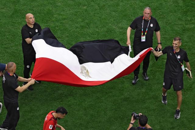 Egypt's head coach Hossam Hassan (L) holds a national flag with staff members as they celebrate winning the 2026 World Cup round of 32 football match between Australia and Egypt at the Dallas Stadium in Arlington on July 3, 2026.  (Photo by Aric Becker / AFP)